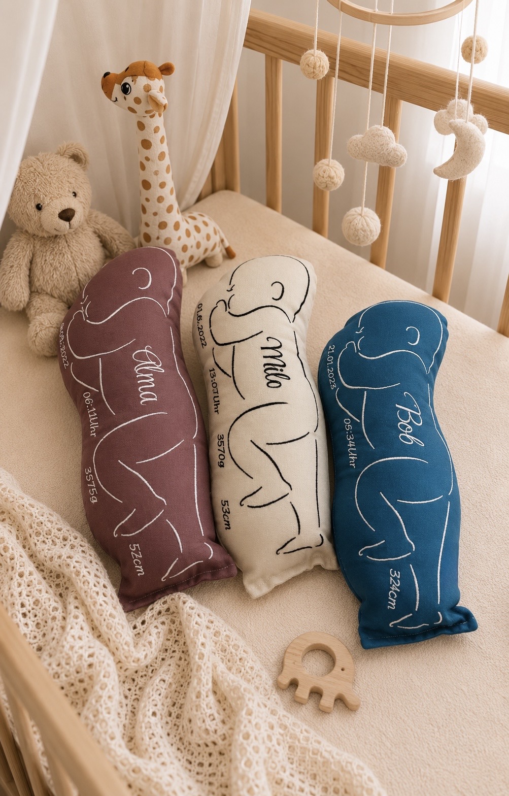 Drei Kissen in Babyform im Babybett